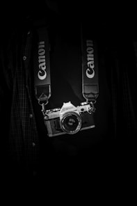 gray and black Canon camera body with lanyard