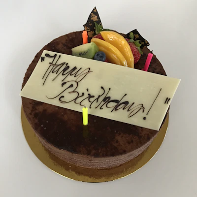 An elegant chocolate birthday cake topped with fresh berries and a subtle shimmer of champagne gold.