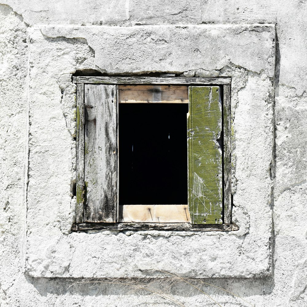 ventana de madera verde sobre pared de hormigón blanco