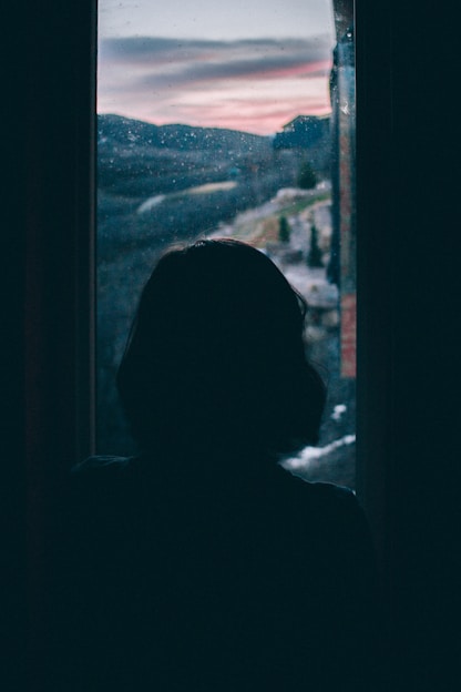 women's silhouette facing outside window