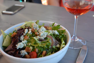 A colorful salad with mixed greens, nuts, and dried cranberries, paired with a chilled rosé wine.