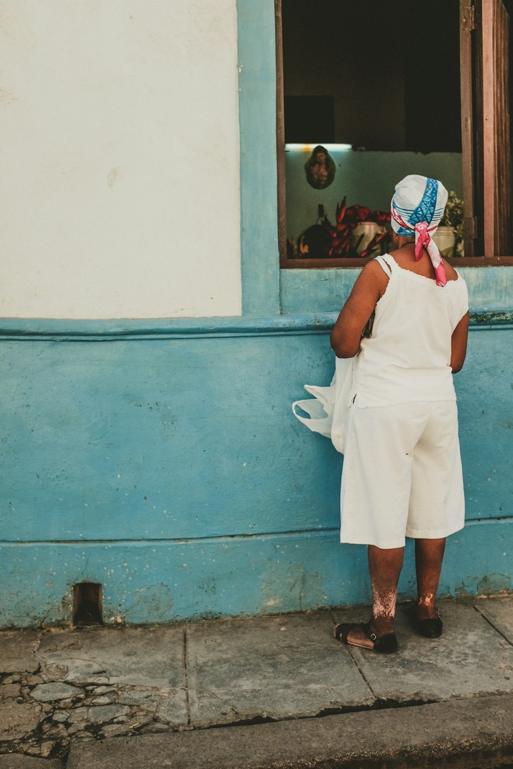 femme portant une camisole blanche regardant à l’intérieur de la fenêtre