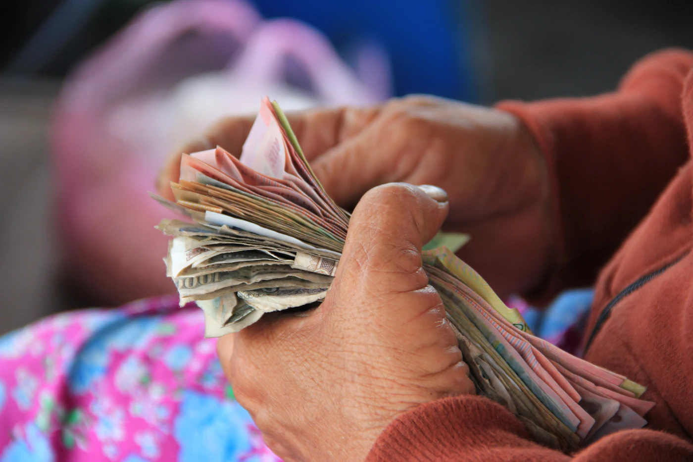 Manos contando un fajo de billetes en Hội An, Vietnam