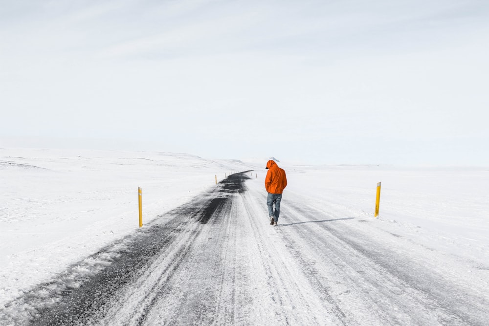 uomo che cammina sulla strada innevata