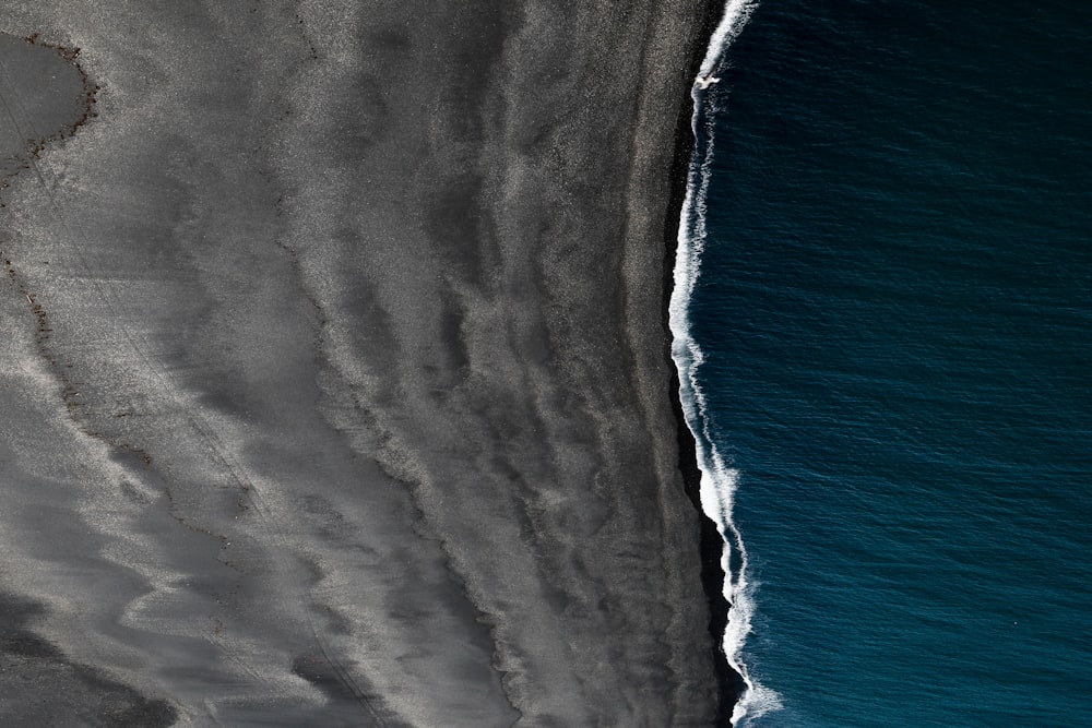 bird's view of black sand and body of water