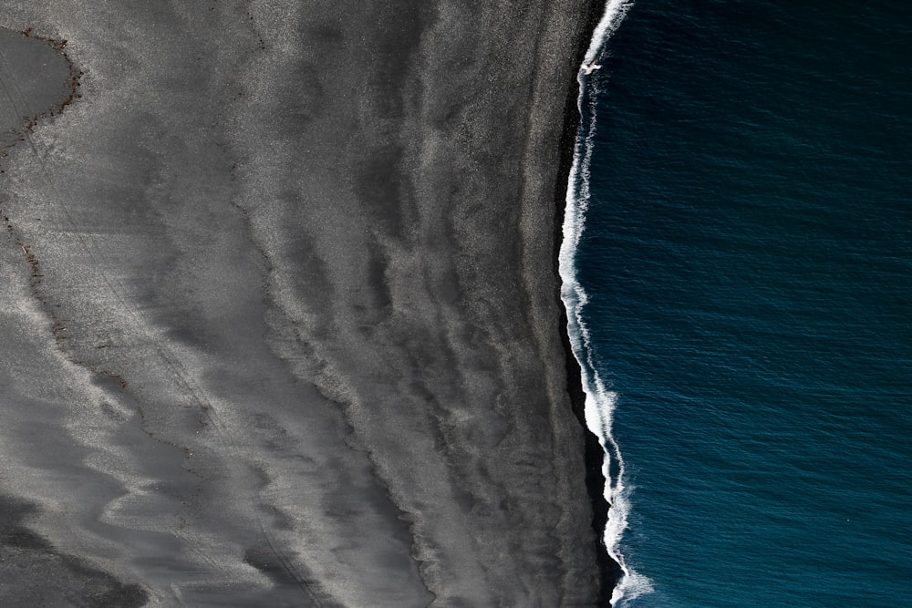 Vista de pájaro de arena negra y cuerpo de agua