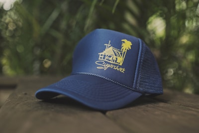 Close-up of a neon green and yellow logo embroidered on a black baseball cap resting on dark wood.