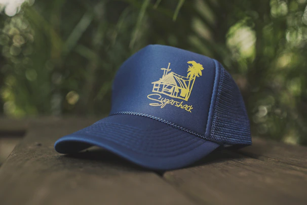 A cozy navy blue hat embroidered with the BuildIt Prints logo resting on a wooden table.