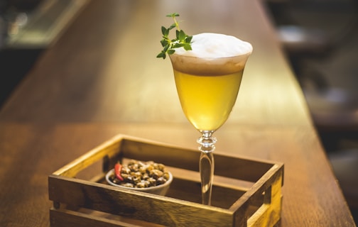 yellow liquid in clear long stem wine glass near cooked food