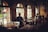 A cozy cafe environment with people sitting at tables, engaged in conversation. Large windows allow natural light to filter in, creating a warm and inviting atmosphere. The interior features wooden tables and a mix of white and dark chairs, with subtle decor enhancing the relaxed vibe.