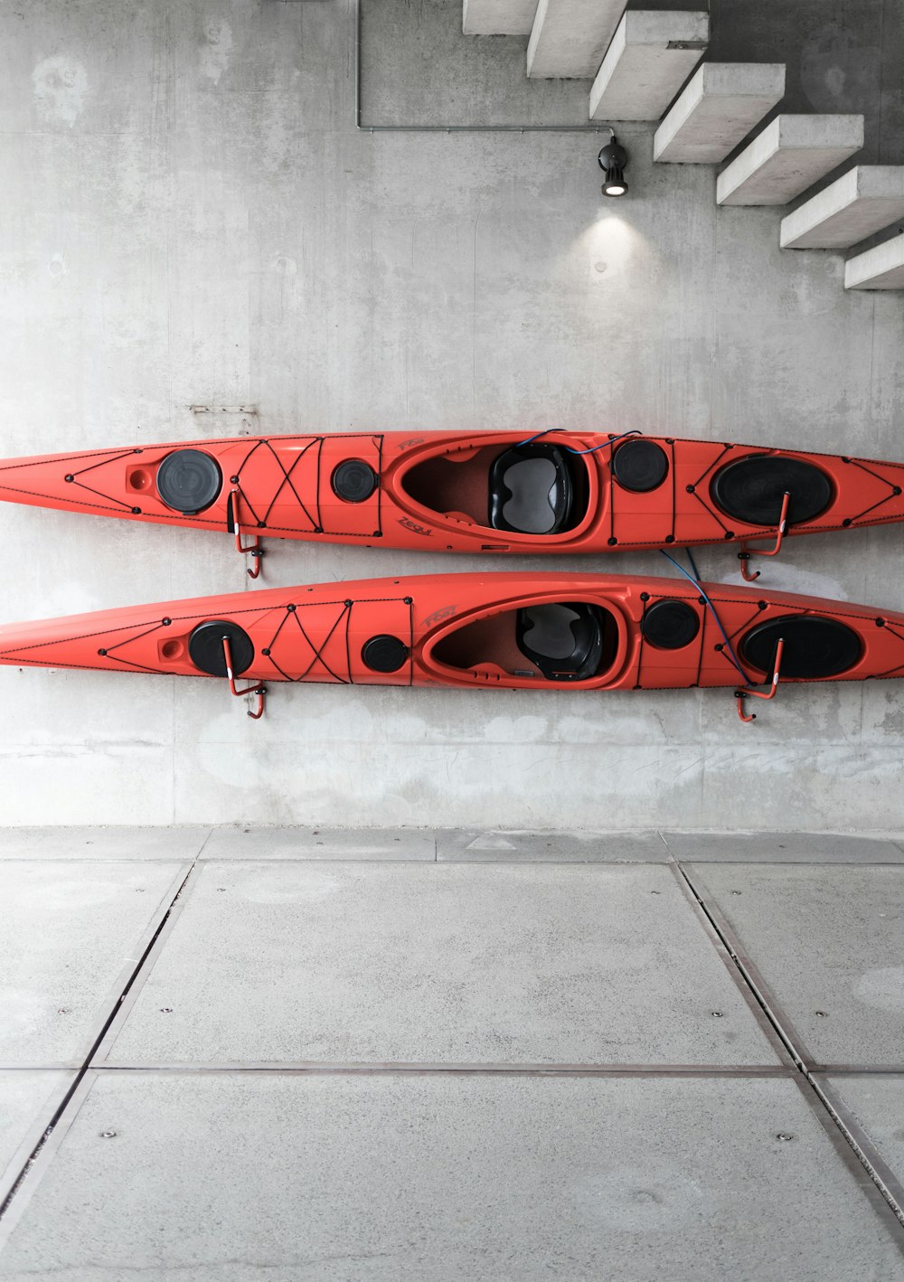 two red kayaks hanging on wall under stairs