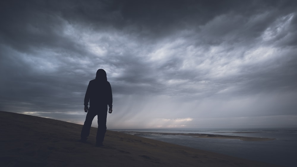 Fotografía de silueta de persona bajo nubes grises