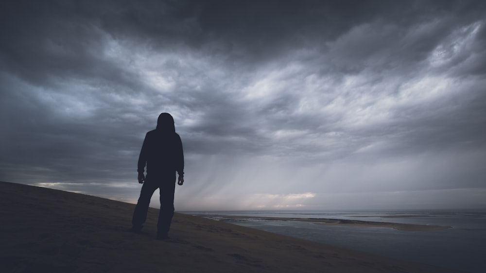 silhouette photography of person under gray clouds