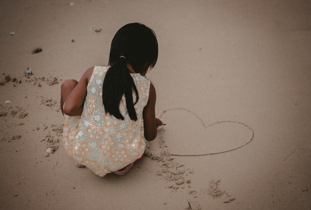 toddler writing heart on sand