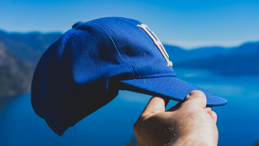 person holding blue fitted cap