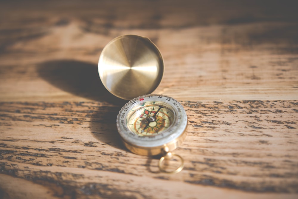 shallow focus photography of compass on brown table