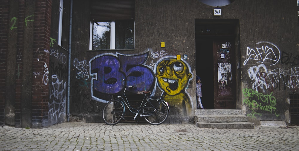 Bicicleta preta estacionada perto da parede marrom