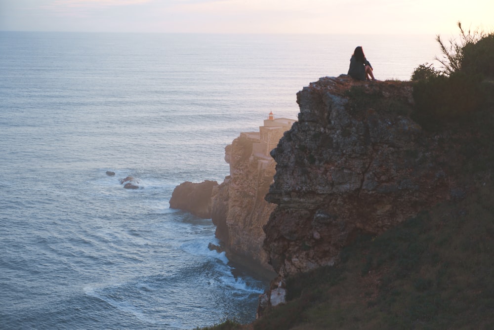 woman sitting on rock near cliff