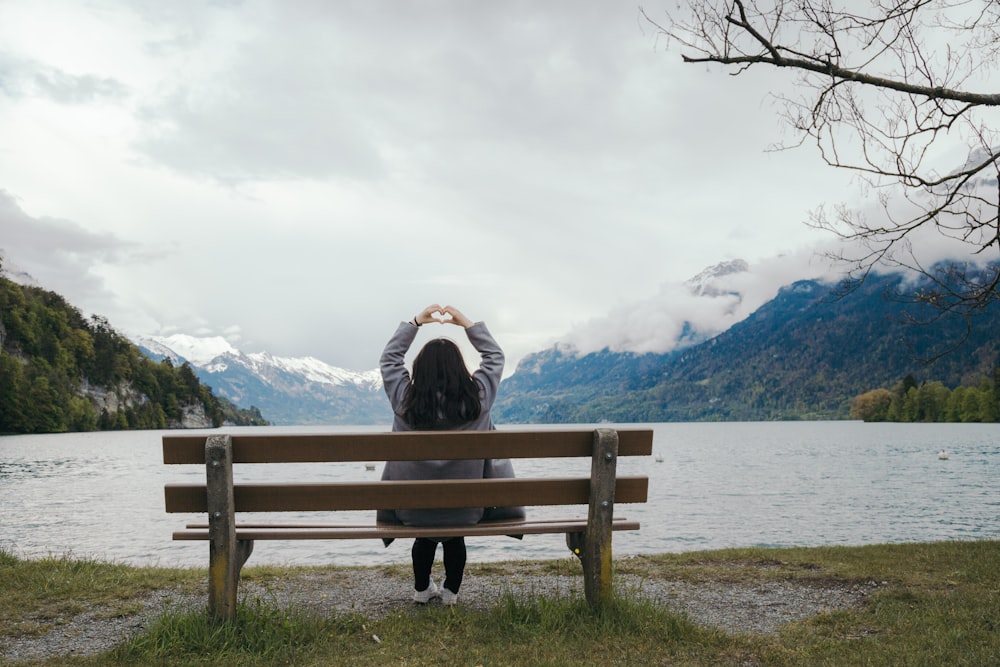 a woman sitting on a bench looking out over a lake