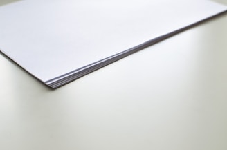 A stack of plain white paper on a smooth light-colored surface, with the edges aligned neatly.