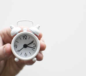 person holding white mini bell alarmclock