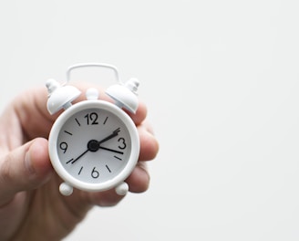 person holding white mini bell alarmclock