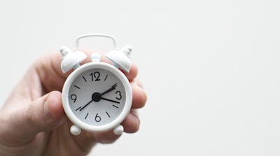 person holding white mini bell alarmclock