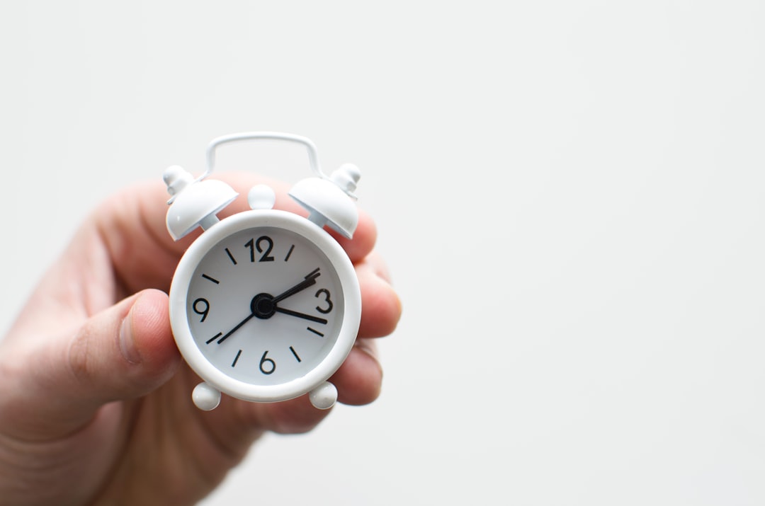  person holding white mini bell alarmclock clock