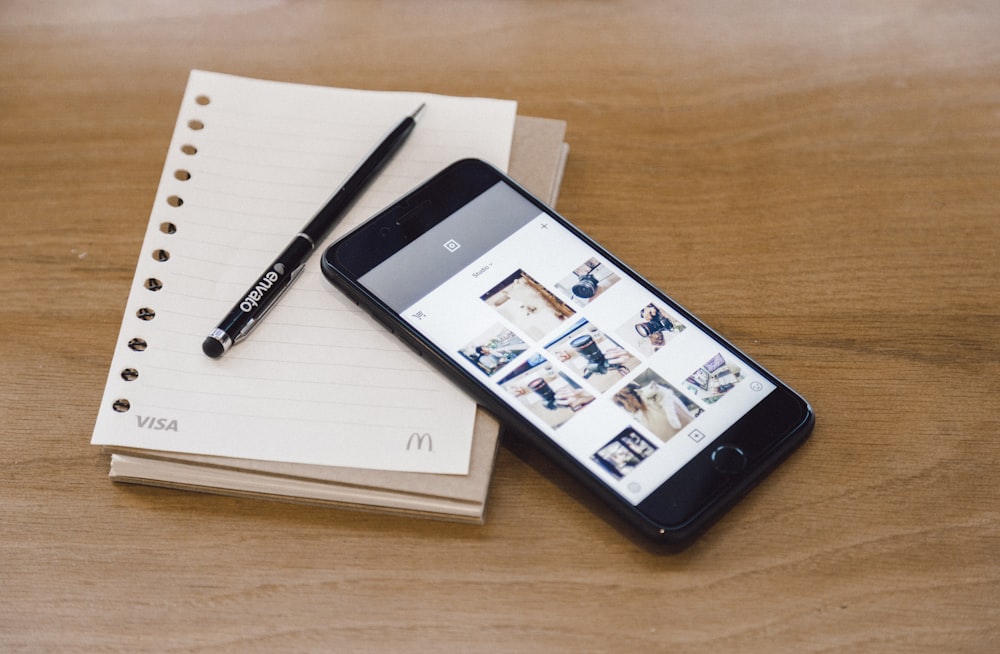 Um smartphone, caderno e caneta.