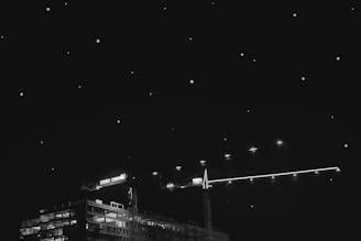 Wide shot of a brightly lit construction site illuminated by a tall solar lighting tower against a dark sky.