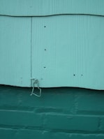 Close-up of adhesive wall hooks holding keys and small plants on a textured wall.