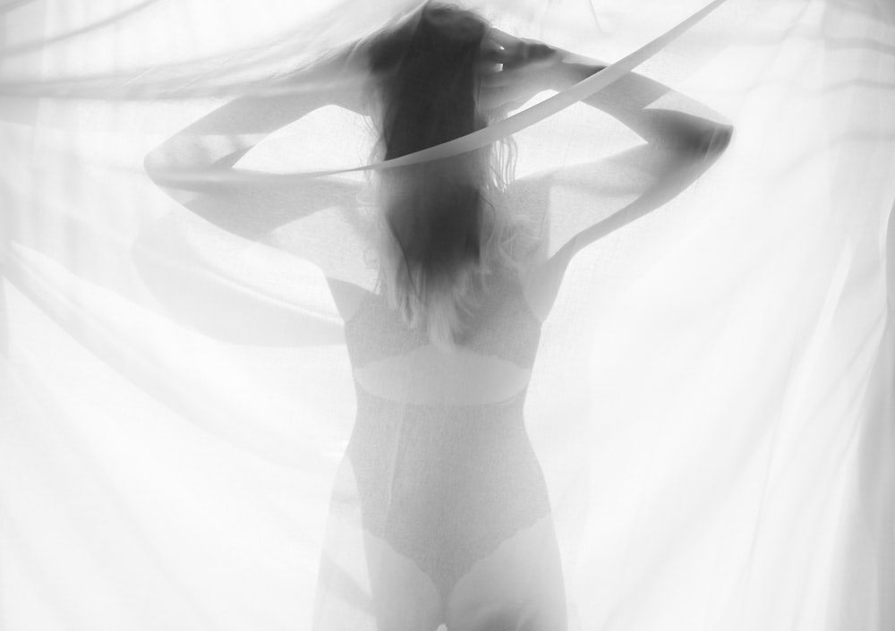 a woman standing in front of a sheer curtain