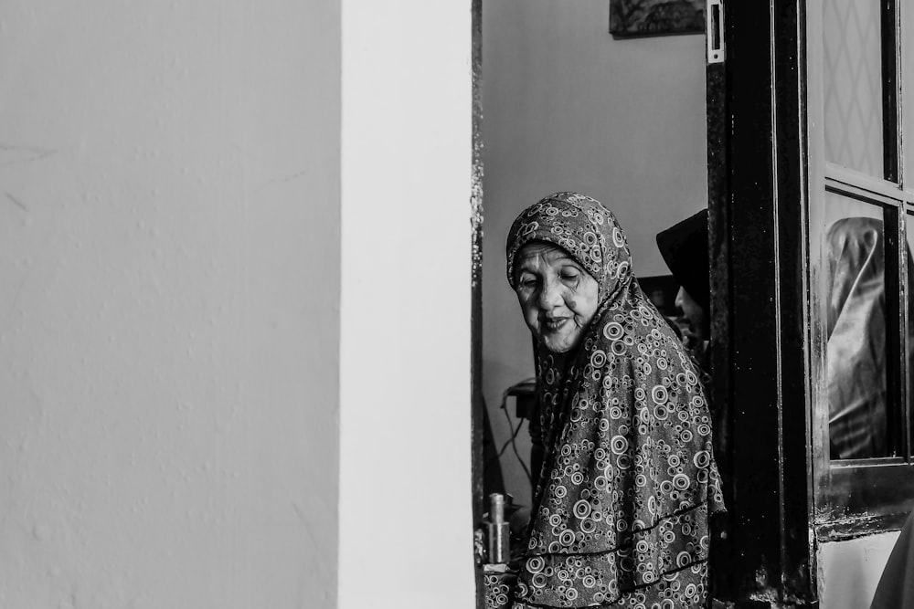 grayscale photo of woman between doors