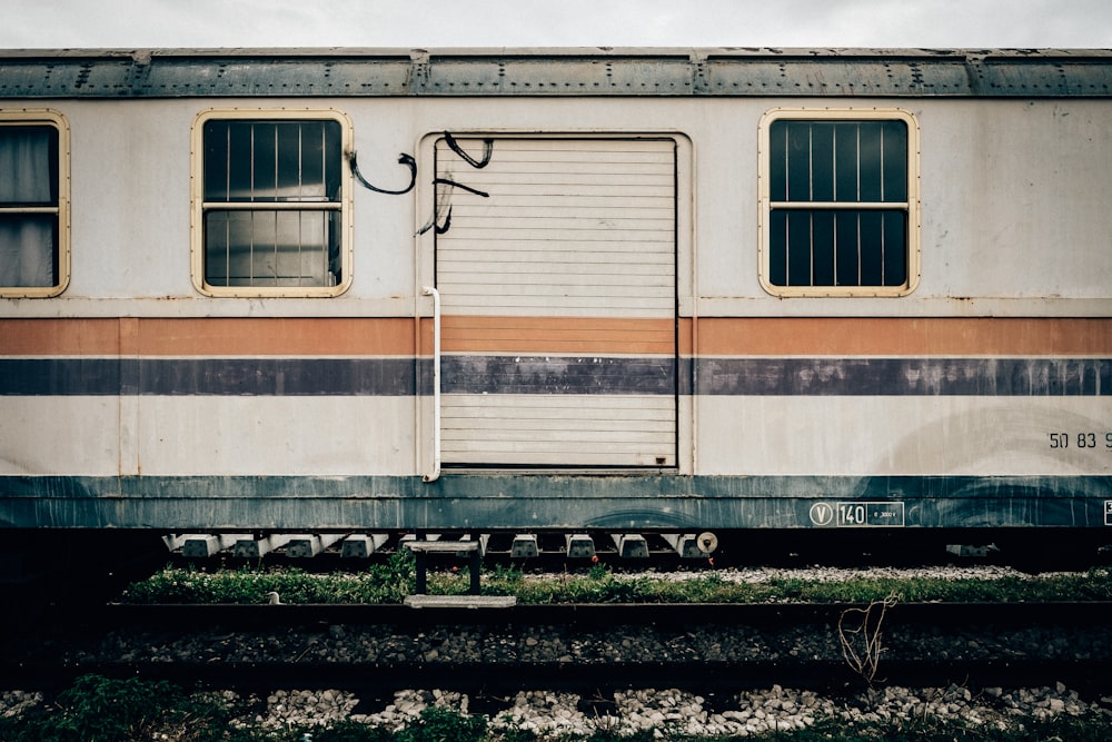 white and orange train on railway