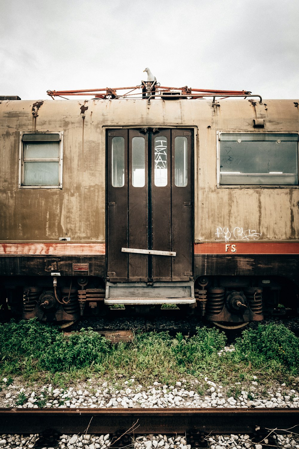 Trem abandonado marrom e preto sobre trilhos durante o dia