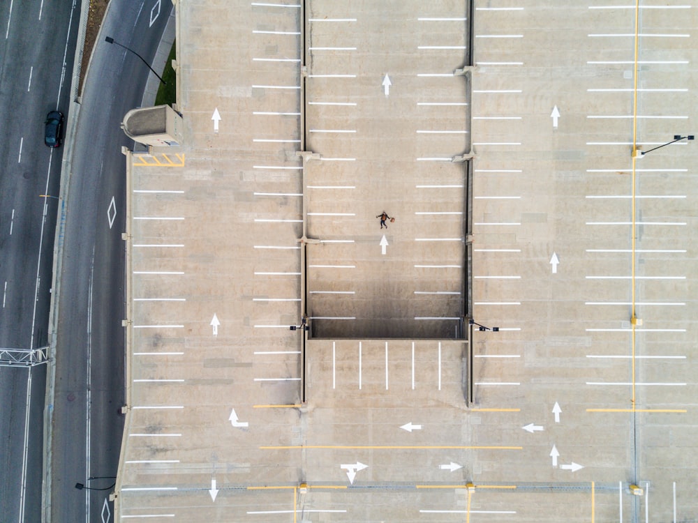 person lying on gray concrete parking area in aerial photography