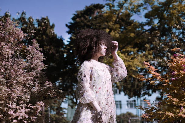 A vibrant seasonal dress with floral patterns, flowing gently in a breezy outdoor garden setting.