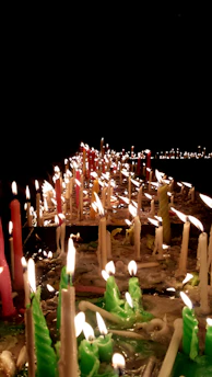 A serene medium connecting with spirits surrounded by gentle candlelight and vibrant LGBTQIA colors.