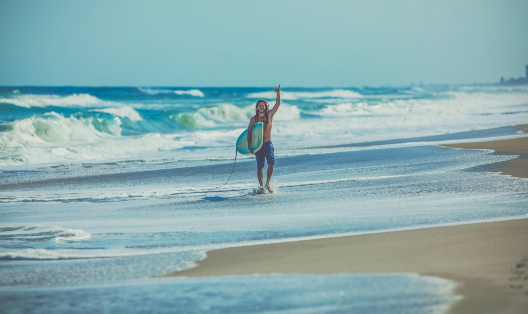man carrying surfboard at beach