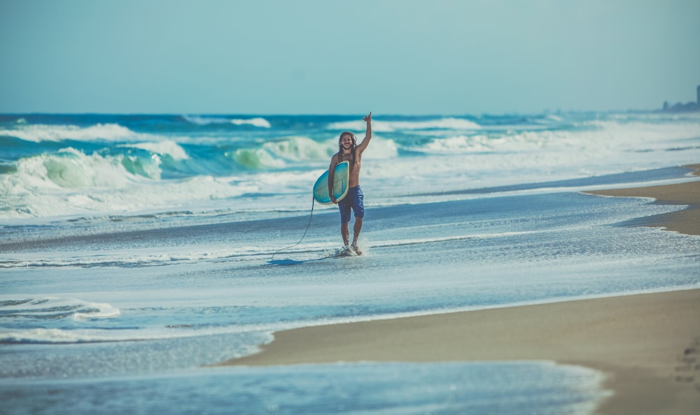 man carrying surfboard at beach