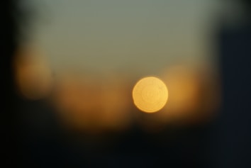 A blurred image with a prominent circular light source in the center against a background of warm hues and soft gradients.