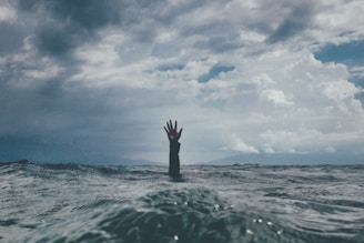 Eine Hand ragt aus stürmischen Wellen, symbolisiert die Herausforderungen eines Wachstumsunternehmen