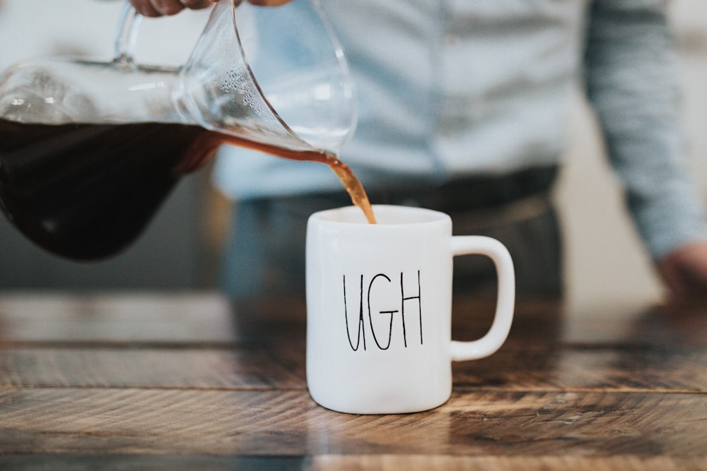 A barista pouring coffee into a mug that says ugh on it at Bar Nine