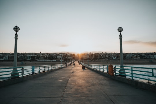 photography of person walking on bridge during daytime in Manhattan Beach Pier United States