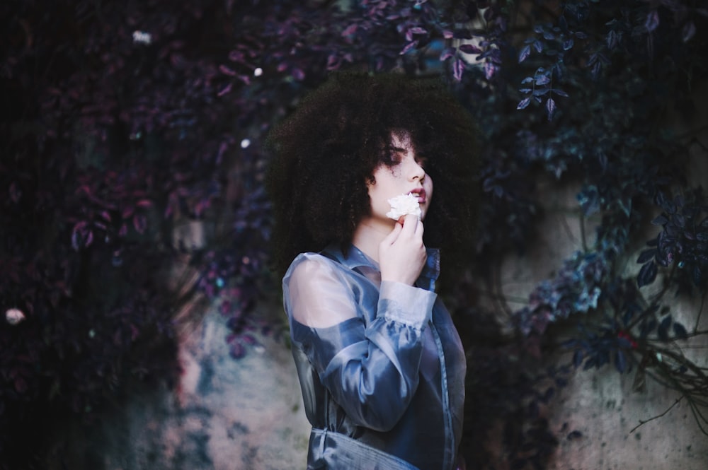 woman standing beside flower wall