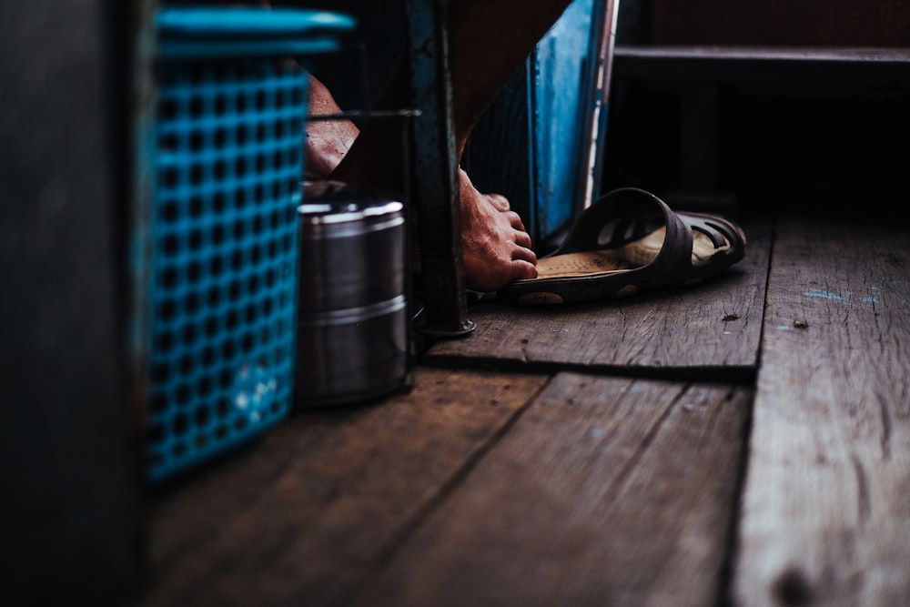 person reaching sandal with his foot