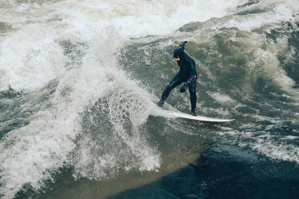 man on white surfboard while surfing