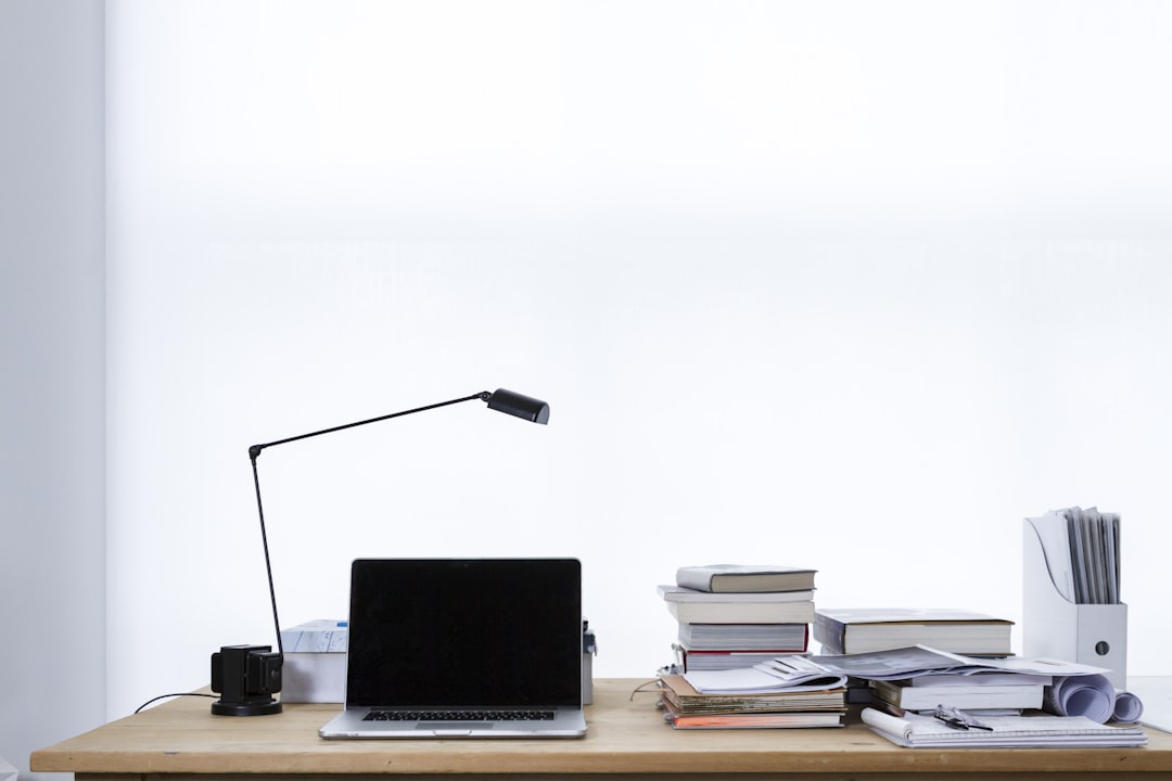 MacBook Pro on top of table, Laptop on desk book stacks