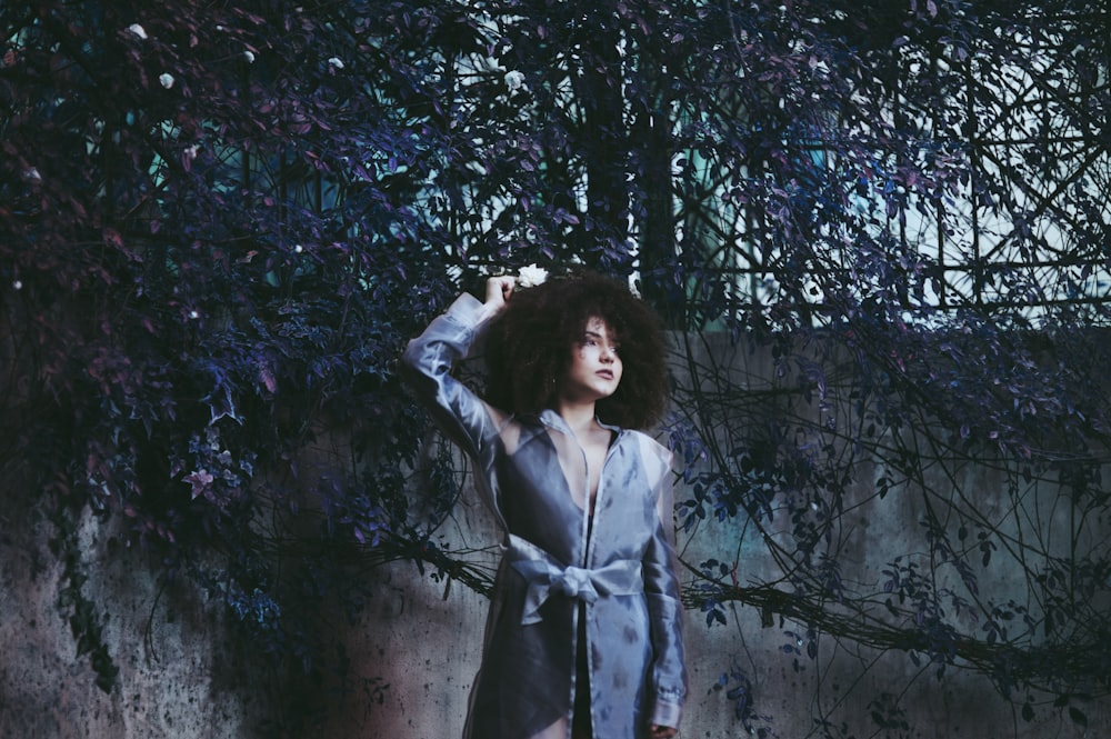 woman posing near wall with tree