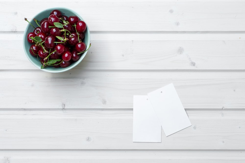 cherries in bowl beside paper